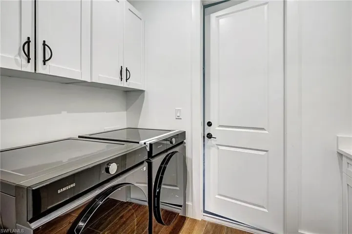 Laundry area with cabinets, dark hardwood / wood-style flooring, and washing machine and dryer