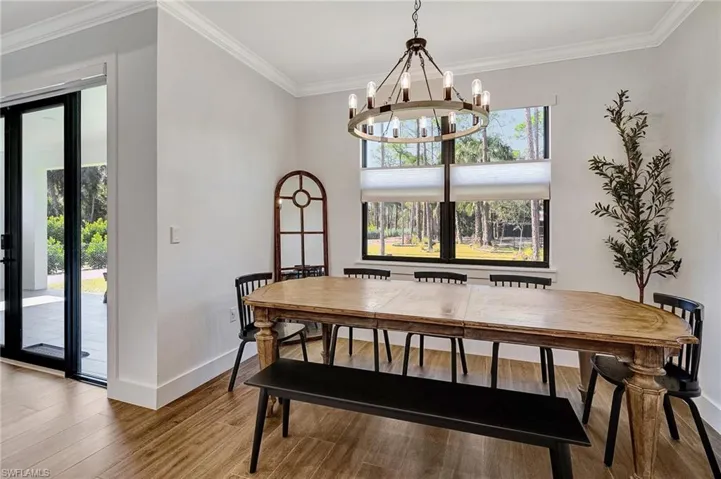 Dining space with crown molding, a chandelier, and hardwood / wood-style flooring