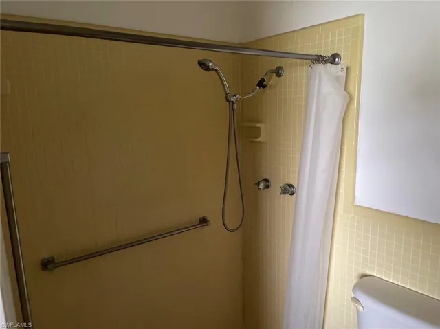 Bathroom featuring tile walls, toilet, and a shower with curtain