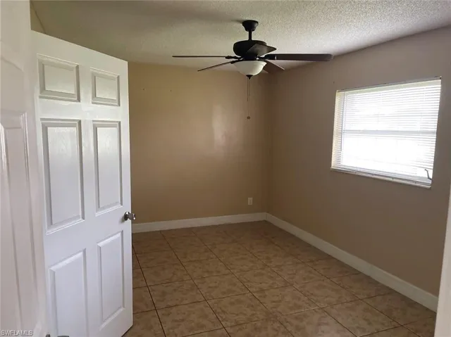 Spare room with tile patterned flooring, ceiling fan, and a textured ceiling