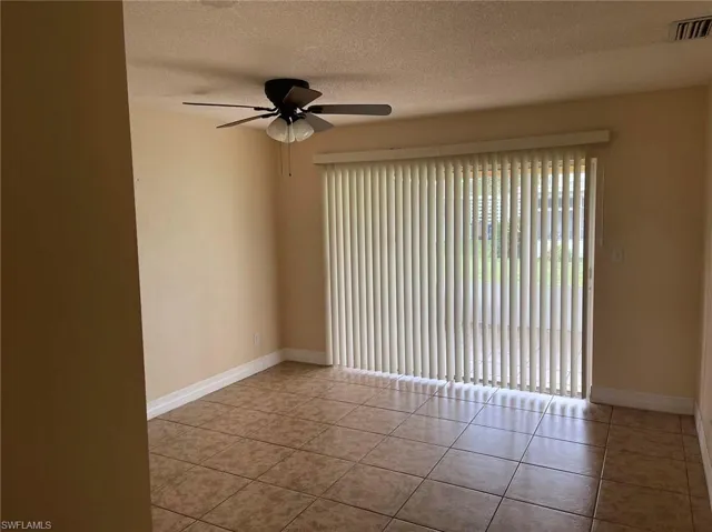 Tiled spare room with a textured ceiling and ceiling fan
