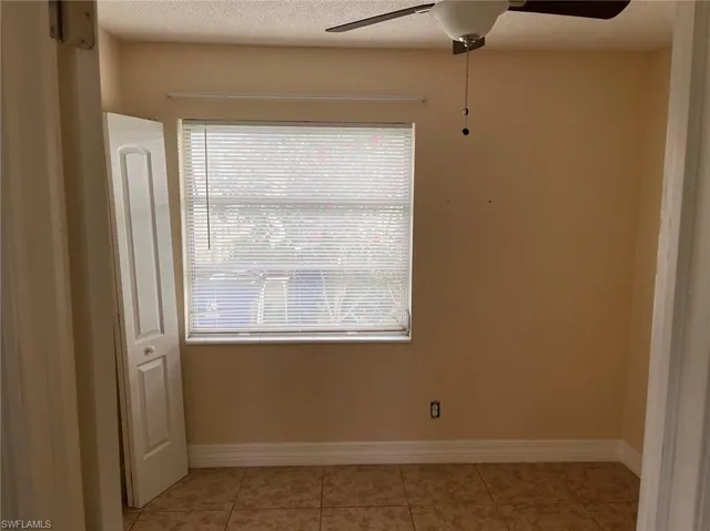 Tiled empty room featuring a textured ceiling, a wealth of natural light, and ceiling fan