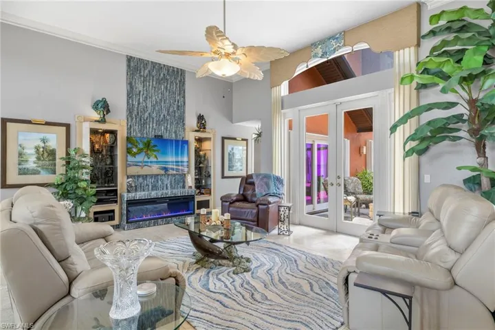 Living room featuring floor to ceiling hologram fireplace, french doors, a high ceiling, and ornamental molding