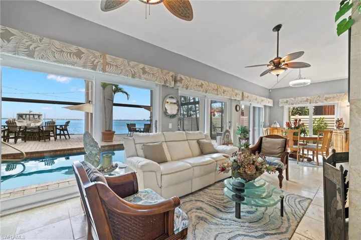 Living room with ceiling fan, a water view, and vaulted ceiling