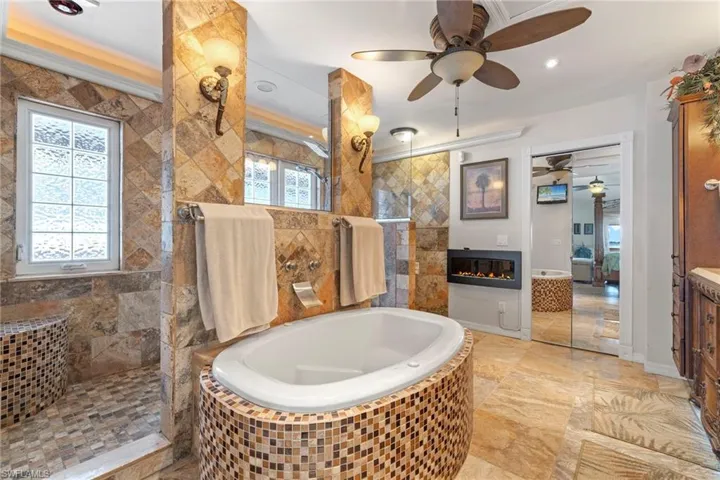 Bathroom featuring shower with separate bathtub, vanity, plenty of natural light, and lighted crown molding