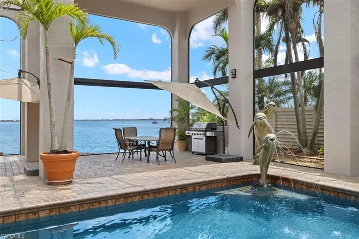 View of swimming pool featuring a grill, pool water feature, a patio area, and a water view