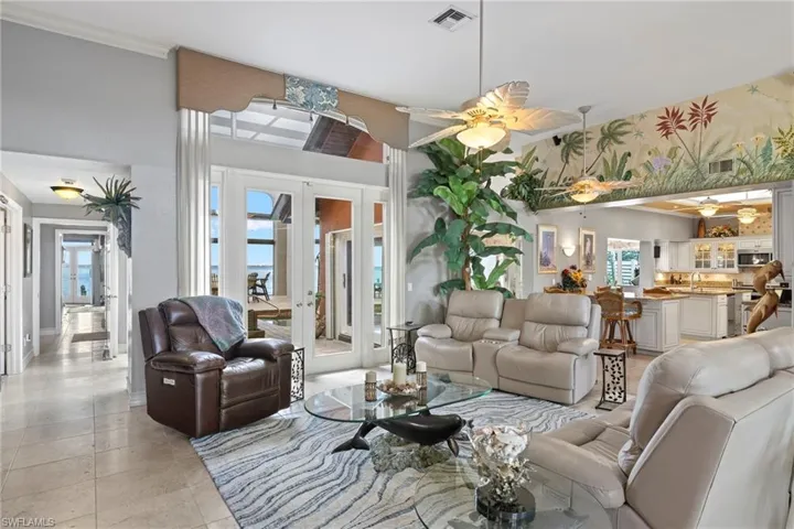 Living room with ceiling fan, travertine light tile patterned flooring, sink, and french doors