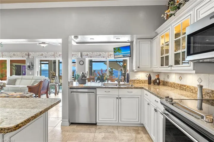 Kitchen with sink, tasteful backsplash, undercounted lighting, white cabinets, and appliances with stainless steel finishes