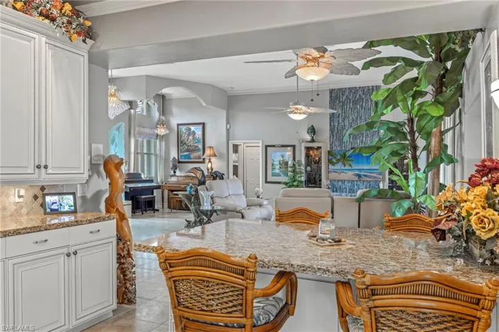 Kitchen with white Maple cabinetry, decorative backsplash, crown molding, and ceiling fan