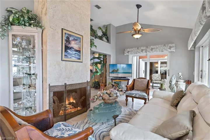 Living room featuring ceiling fan, a large wood burning fireplace, and high vaulted ceiling
