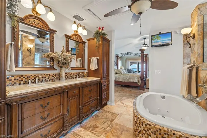 Bathroom with tiled tub, double vanity and motion lighting