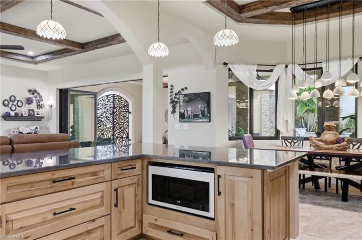 Central kitchen island with wood-finish cabinetry and a dark stone countertop
