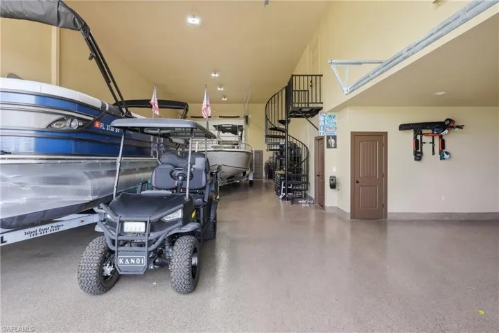 Massive/Expansive garage with high ceilings, epoxy flooring, a black spiral staircase, and multiple brown panel doors