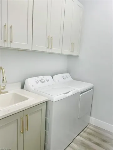 Laundry room featuring washing machine and dryer, light wood finished floors, and cabinet space
