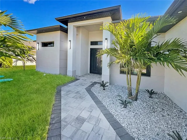 Doorway to property featuring stucco siding and a lawn