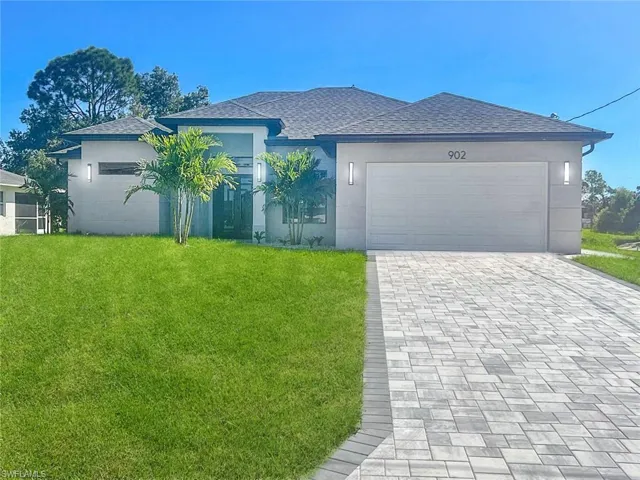 Ranch-style home featuring roof with shingles, a front lawn, decorative driveway, stucco siding, and an attached garage