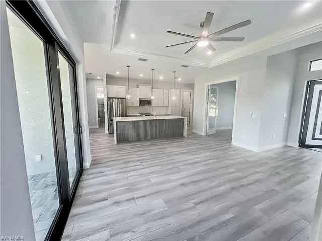 Kitchen with a tray ceiling, open floor plan, light countertops, and recessed lighting