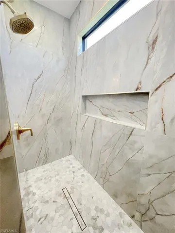 Full bathroom with a marble finish shower
