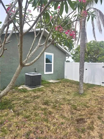 Side yard featuring storm windows,  central air condition unit and a gate entrance to back yard .