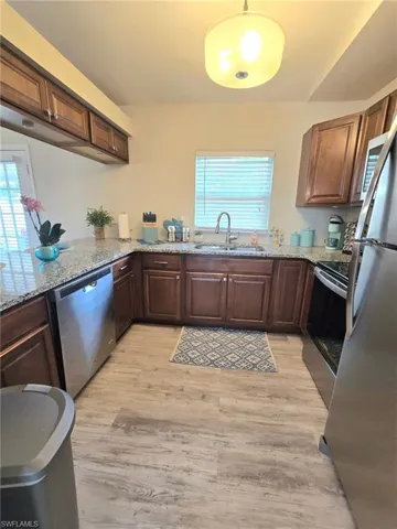 Kitchen featuring appliances with stainless steel finishes, a sink, light wood-type flooring, wood cabinets and healthy amount of natural light
