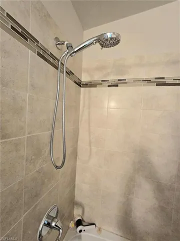 Bathroom featuring  light tiled shower / tub combination tiled and showerhead extension