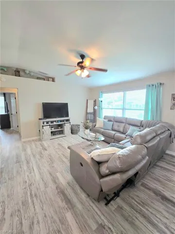 Living room featuring wood finished floors, plenty of natural light, ceiling fan, and baseboards including all furnishings , decor and window coverings