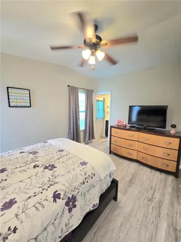Primary Bedroom featuring light wood-type flooring, ceiling fan, and dresser with television