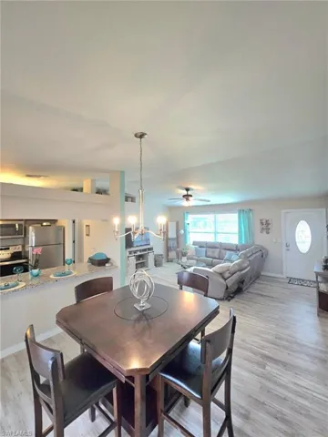Dining space with a chandelier, ceiling fan, and light wood finished floors