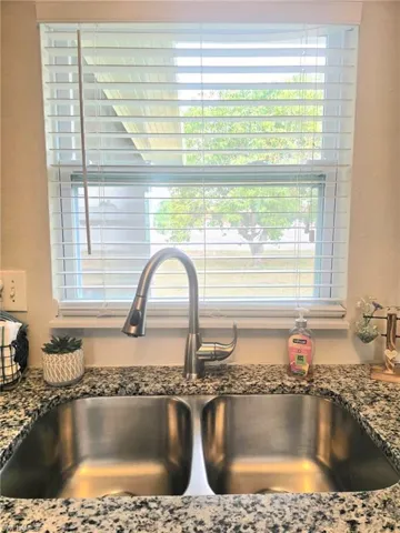Kitchen view of a sink and stone counters with view of private back yard.