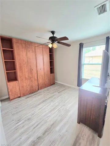Guest bedroom #2 with wall unit murphy bed (closed) , dresser, window coverings, light wood finished floors, baseboards, and ceiling fan