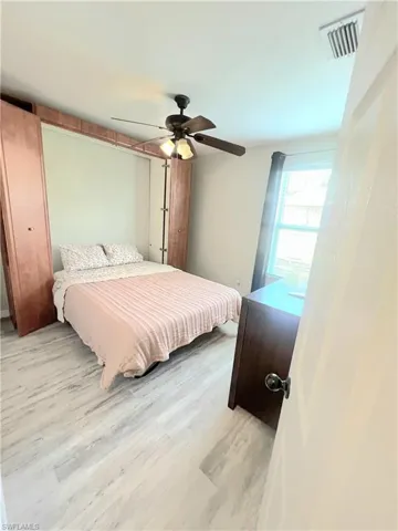 Bedroom #2  featuring wall unit with queen murphy bed(open) with bedding,  wood finished floors and a ceiling fan