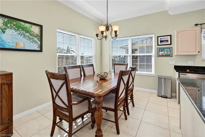 Dining space featuring light tile patterned flooring, ornamental molding, and a chandelier