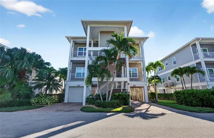 Beach home with stairway, decorative driveway, a balcony, and an attached garage