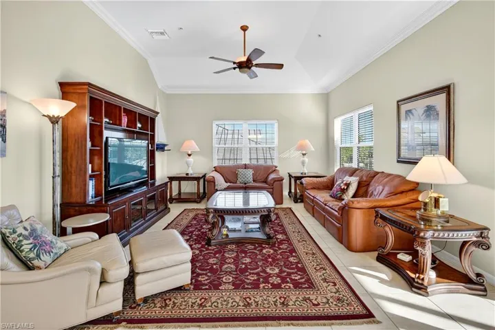 Living area with crown molding, light tile patterned floors, and a ceiling fan