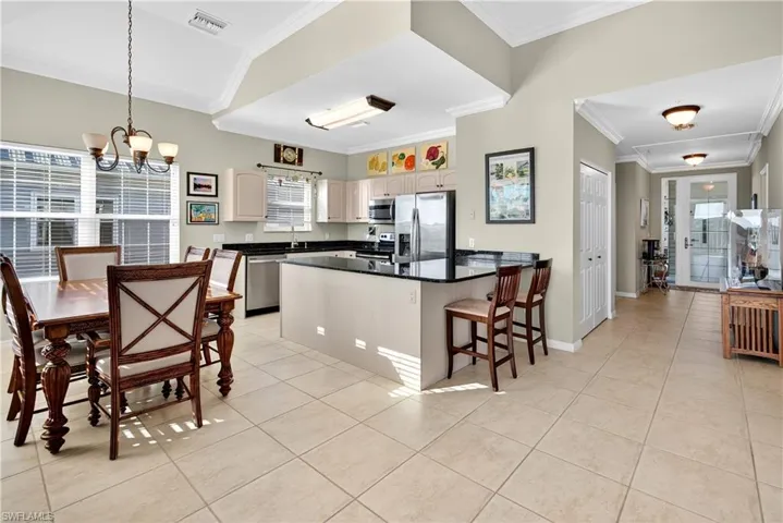 Kitchen featuring a kitchen bar, crown molding, light tile patterned floors, stainless steel appliances, and a chandelier
