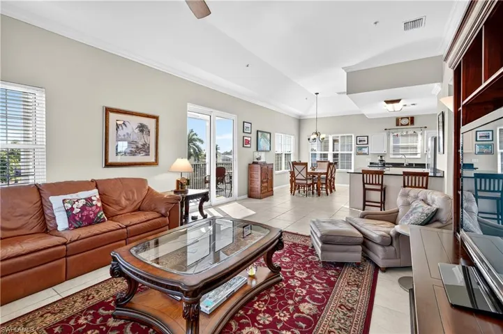 Living room featuring light tile patterned floors, ornamental molding, a chandelier, and ceiling fan