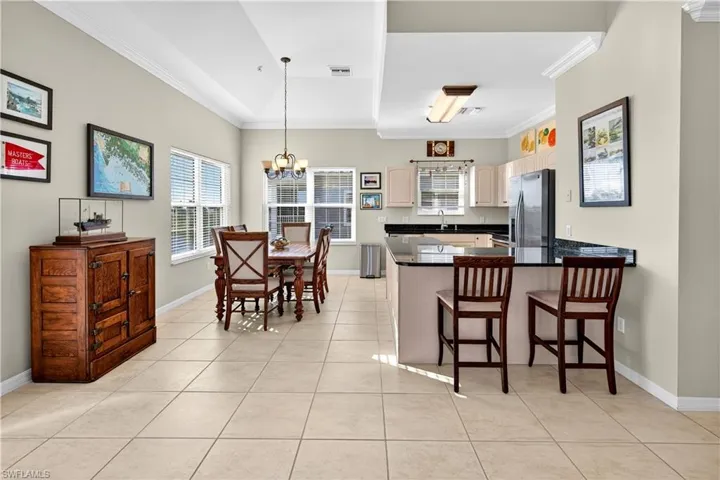 Kitchen featuring a chandelier, ornamental molding, a peninsula, light tile patterned floors, and a breakfast bar area