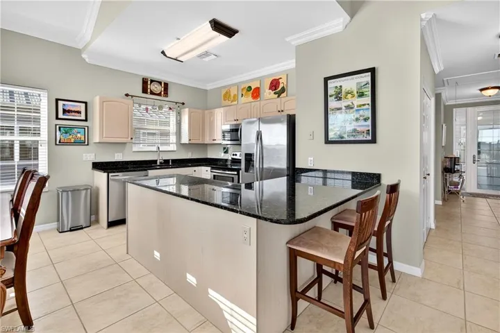 Kitchen featuring crown molding, a peninsula, appliances with stainless steel finishes, a breakfast bar, and light tile patterned floors