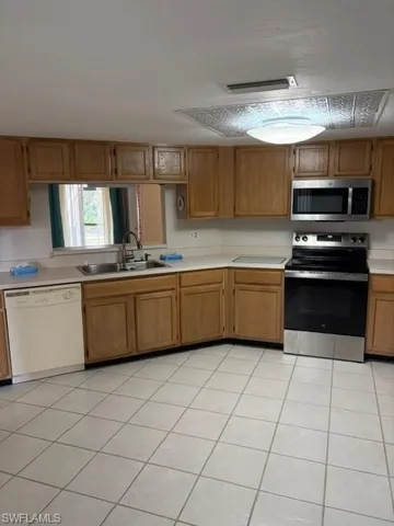 Kitchen featuring stainless steel appliances, light countertops, light tile patterned flooring, and wood finish cabinets