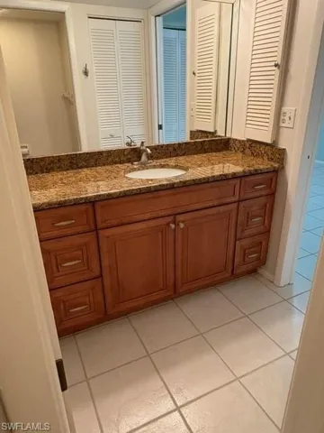 Bathroom featuring light tile patterned flooring, vanity, and a closet