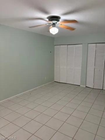 Unfurnished bedroom featuring two closets, ceiling fan, and light tile patterned flooring