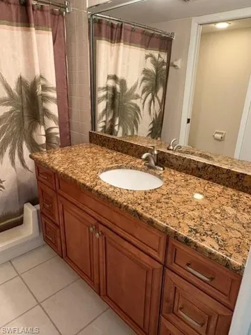 Full bathroom featuring vanity, curtained shower, and light tile patterned flooring