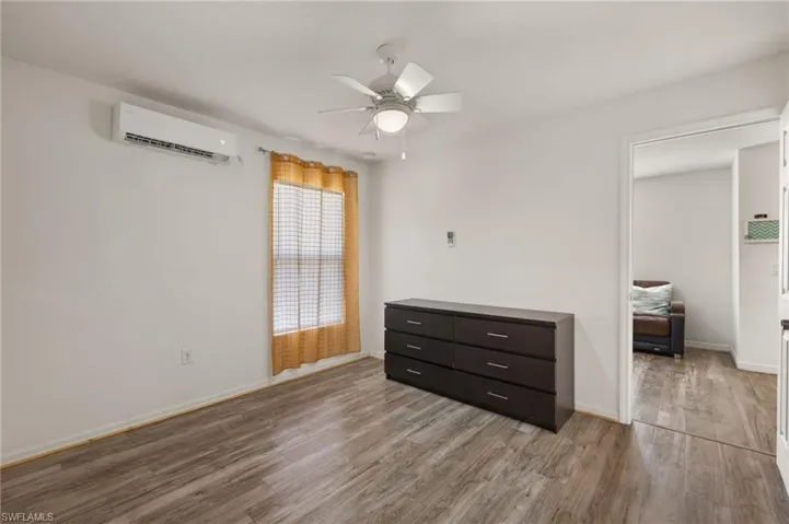 Bedroom featuring a wall mounted AC, ceiling fan, and light hardwood / wood-style floors