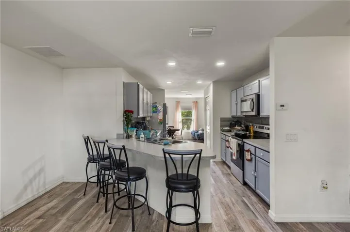 Kitchen featuring kitchen peninsula, a breakfast bar, stainless steel appliances, and light hardwood / wood-style floors