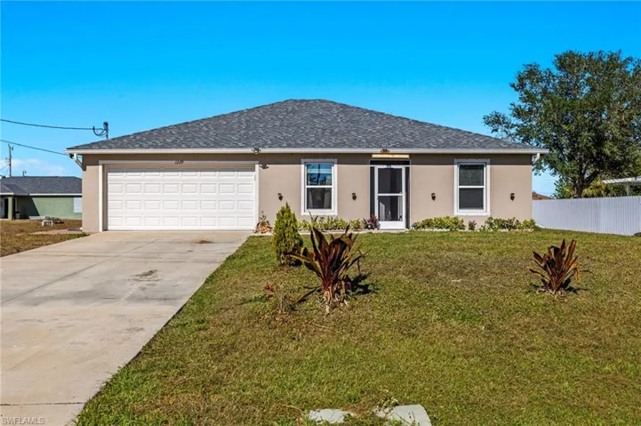 Ranch-style house featuring a front lawn and a garage