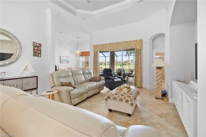 Living area with crown molding, a high ceiling, a raised ceiling, and ceiling fan