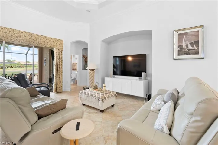 Living area with crown molding, a towering ceiling, light tile patterned floors, and arched walkways
