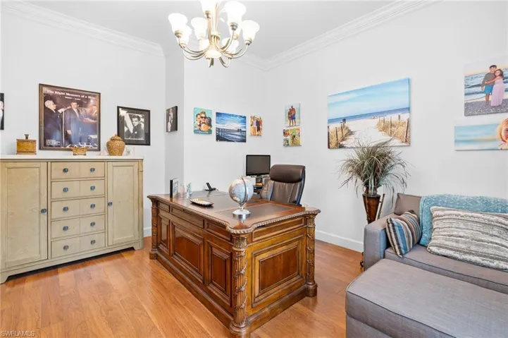 Home office featuring crown molding, light wood-type flooring, and a chandelier