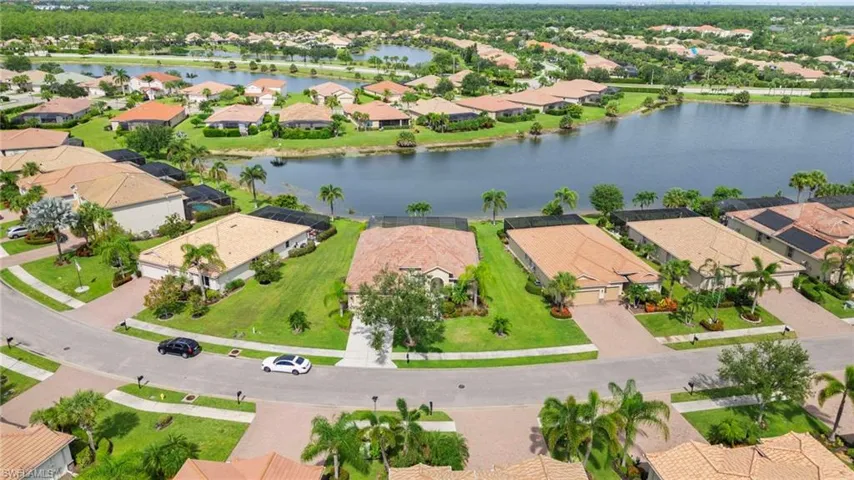 Aerial view of property and surrounding area featuring nearby suburban area and a large body of water