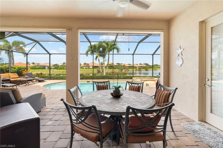 View of patio featuring outdoor dining space, a residential view, a water view, a pool with connected hot tub, and a ceiling fan